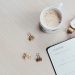 A minimalist desk arrangement featuring a coffee cup, notebook, pen, and wristwatch.
